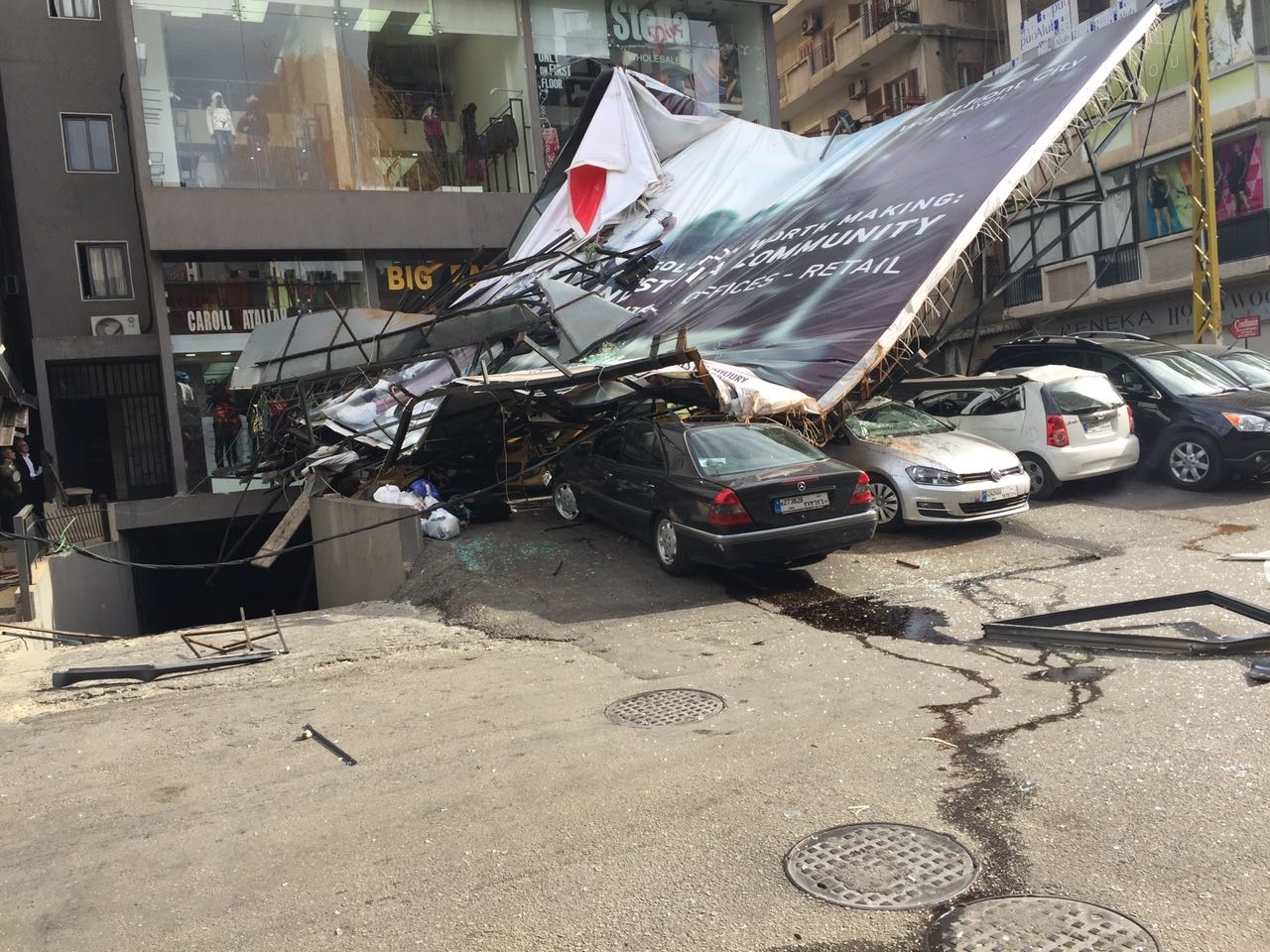 بالصور: سقوط لوحة اعلانية على عدد من السيارات في الزلقا