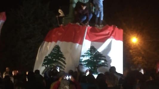 Photo: Protesters in Baakline sign a large Lebanese flag